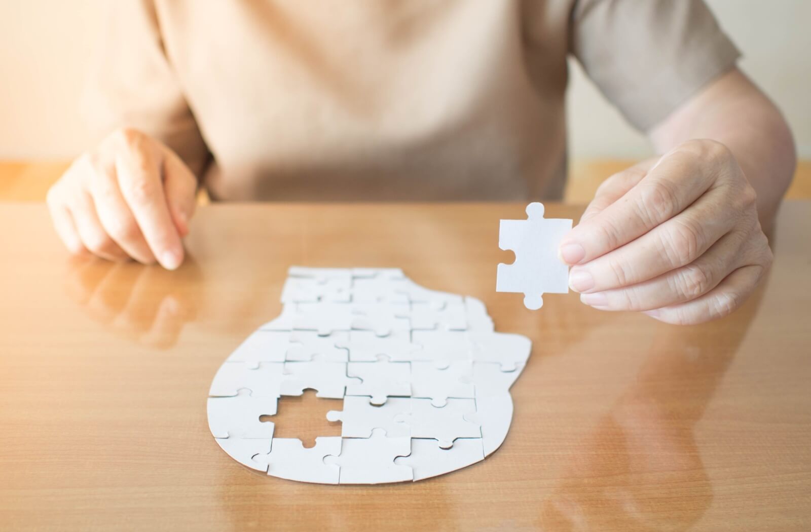 Close-up of a person putting the last missing piece in a puzzle to represent dementia.