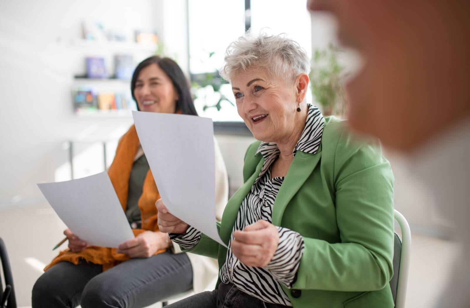 Group of smiling adults holding lyric sheets while singing together in memory care music program