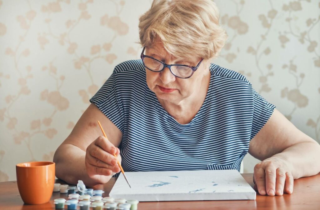 Older adult focused on painting with small brush during memory care art therapy session
