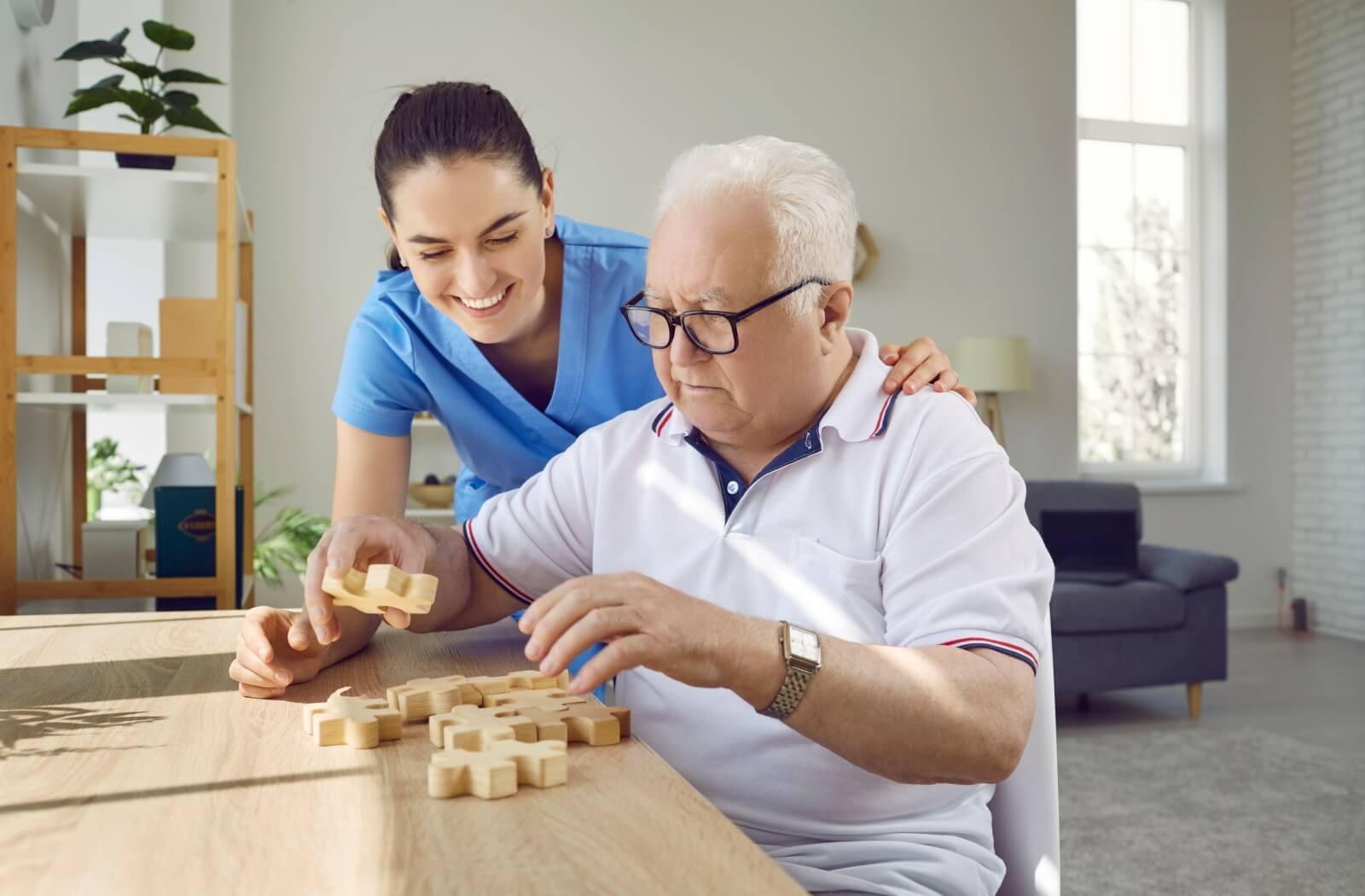 a caregiver helping a senior with a puzzle in memory care